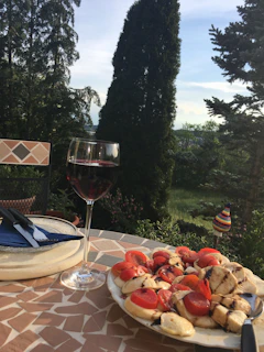 A cozy outdoor table set for a Tuscan meal with wine glasses and fresh bread.