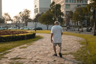 Senior man walking with a trainer in a park, focusing on balance exercises.