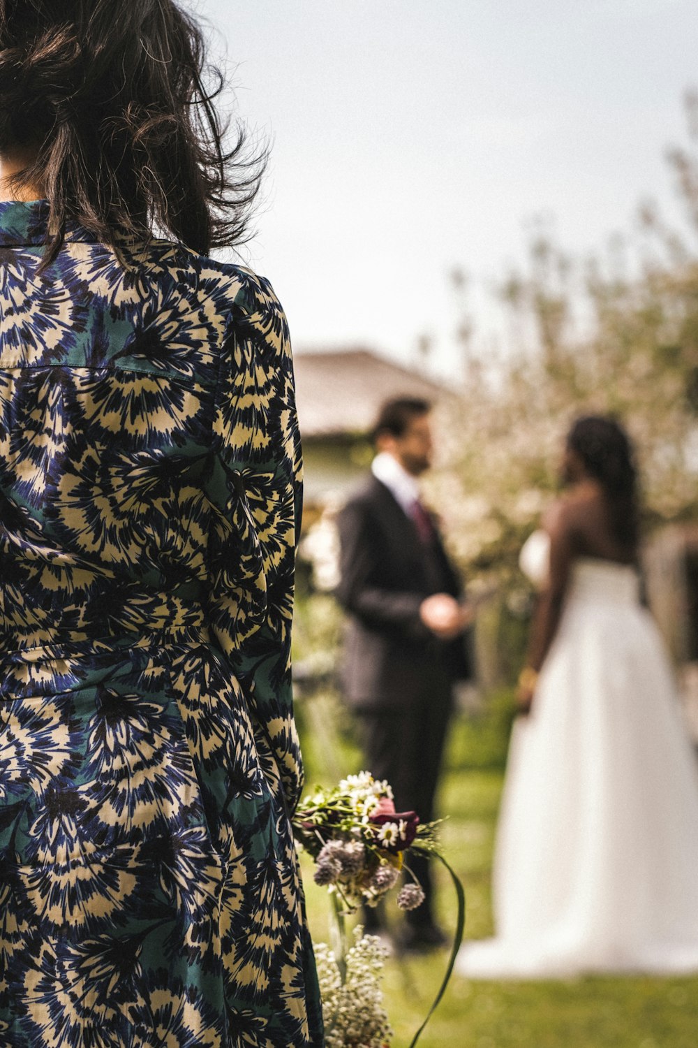 woman in blue and yellow floral dress standing beside man in black suit