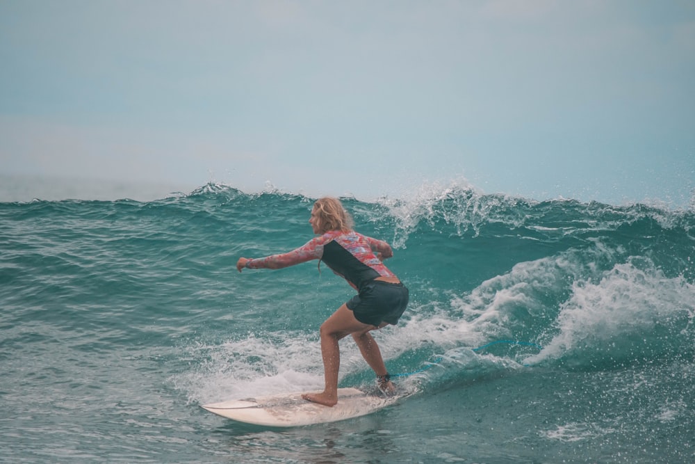 a woman riding a wave on top of a surfboard