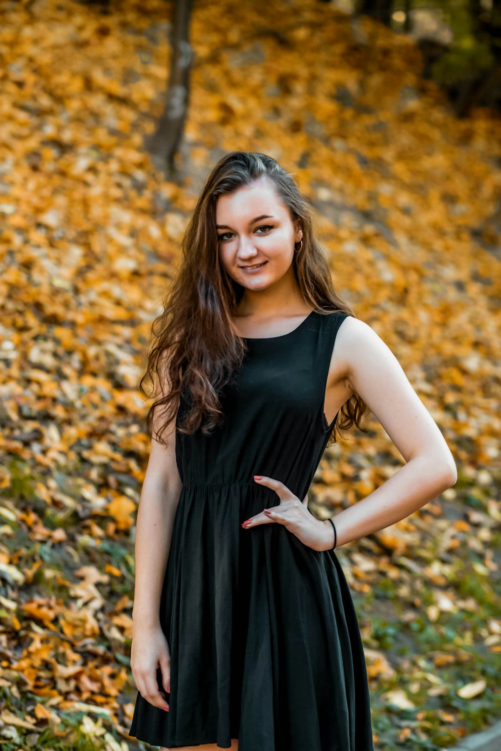 woman in black sleeveless dress standing on brown leaves