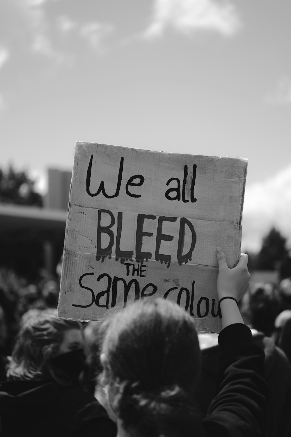 grayscale photo of people holding white and black wooden signage