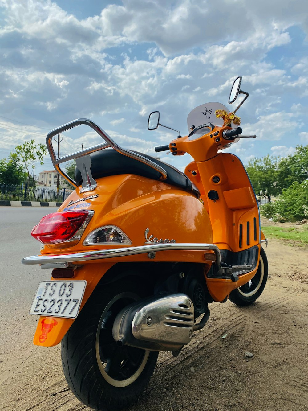 scooter laranja e preto estacionada no pavimento de concreto cinza durante o dia