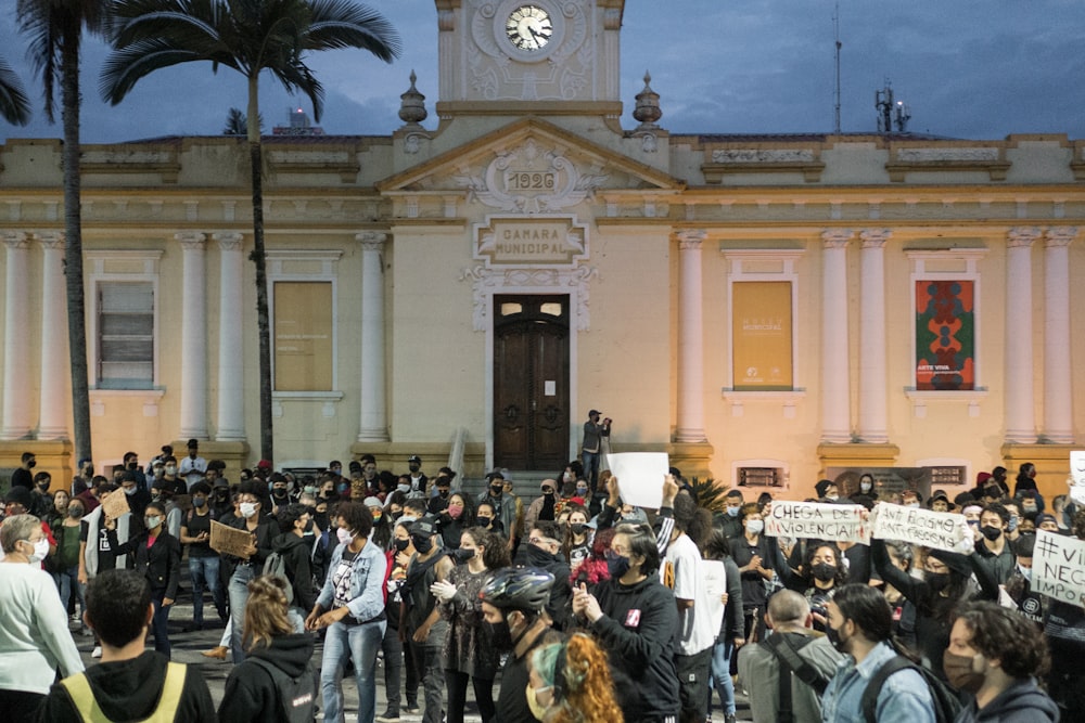 pessoas andando na rua perto do edifício marrom durante o dia