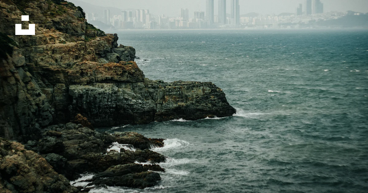 High rise building on rock formation near sea during daytime photo ...