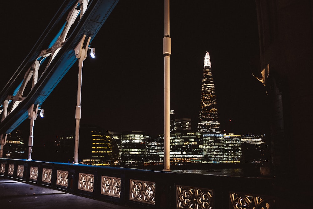 blue and black bridge near city buildings during night time