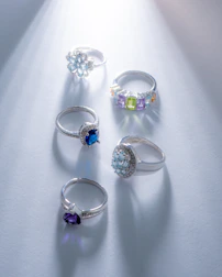 A collection of sparkling gemstone rings with vibrant colors under soft lighting.