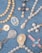 A collection of religious-themed jewelry arranged on a blue denim fabric. The pieces include beaded rosaries, pendants, and medals featuring pearls and gold accents, with some displaying religious icons and symbols.