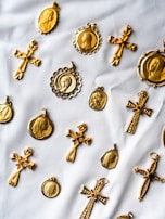 Collection of ornate crosses with rich textures and gold highlights arranged on a white marble surface.