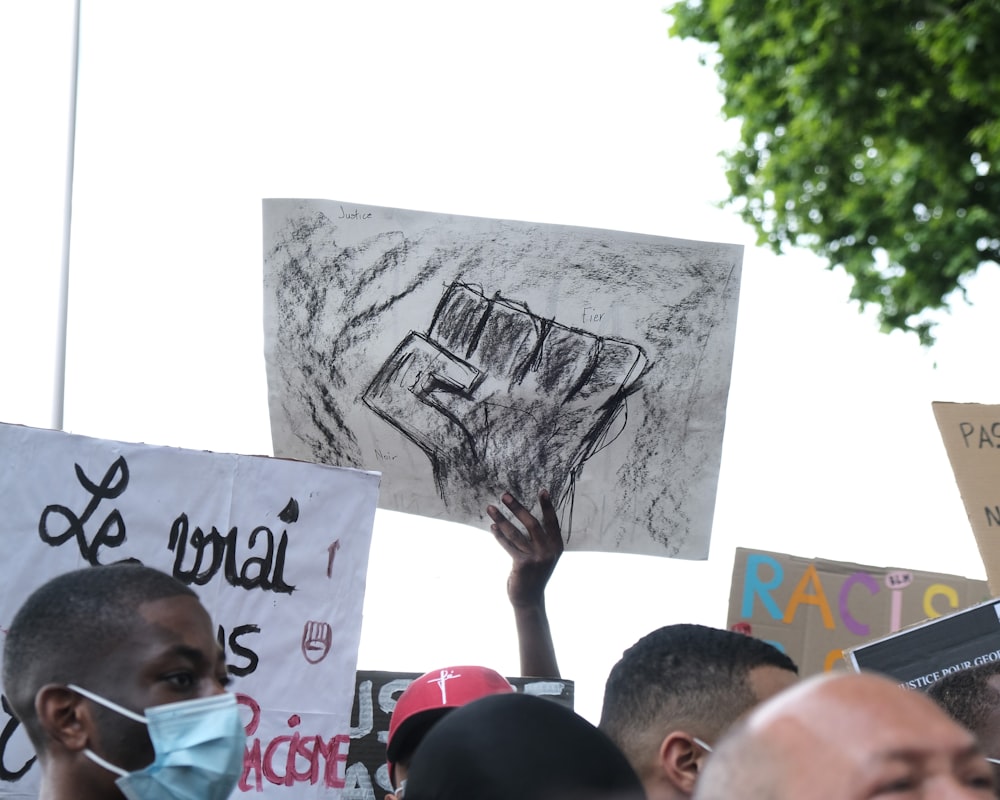 man in black shirt holding white and black poster