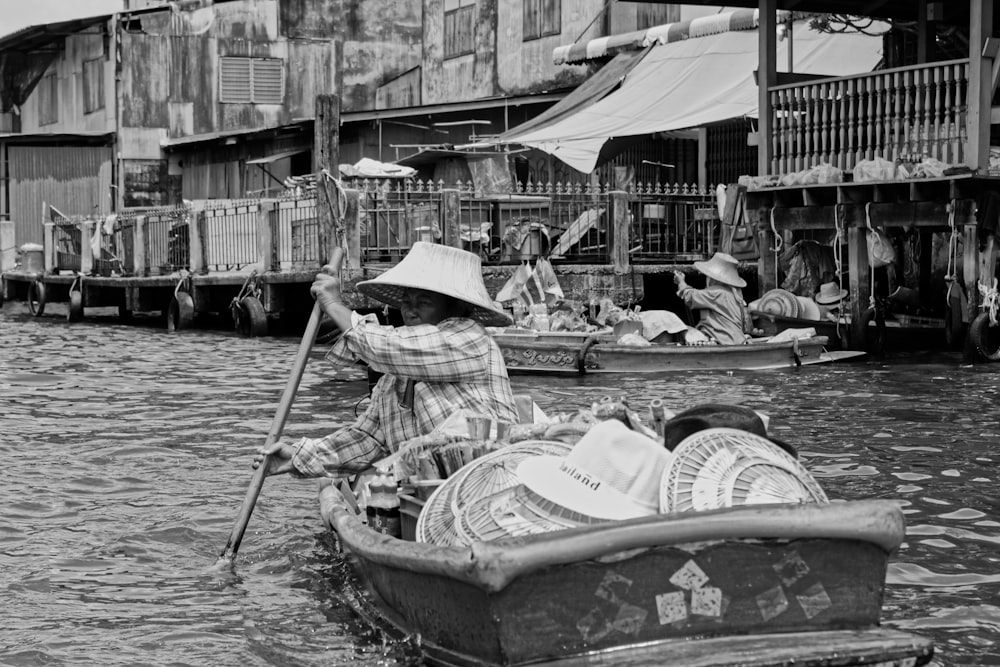 grayscale photo of people riding boat on river