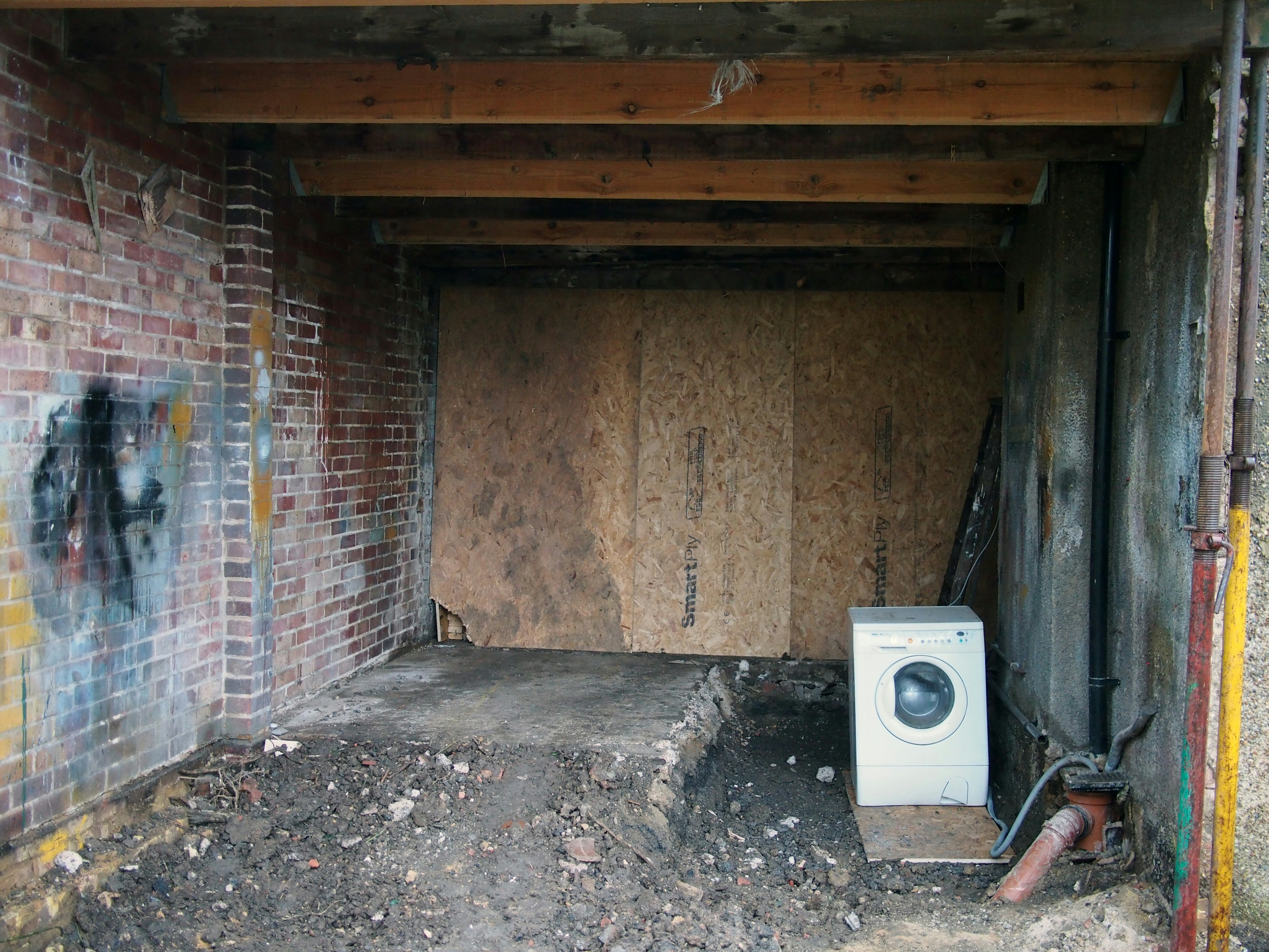 white front load washing machine beside brown brick wall