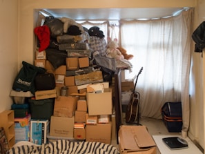 A cluttered living room filled with boxes and scattered belongings before a senior downsizing.