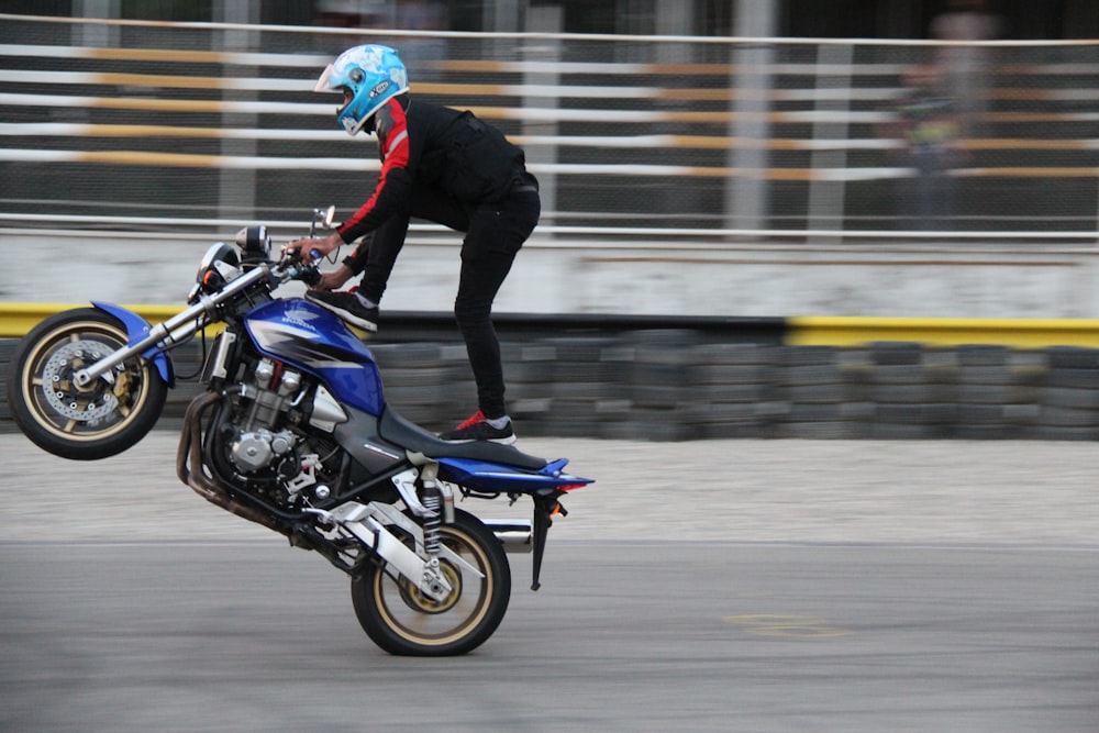 man in black jacket riding blue sports bike