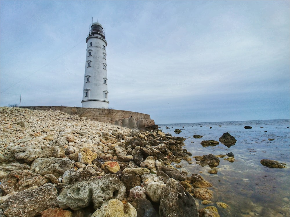 white and black lighthouse on rocky shore during daytime