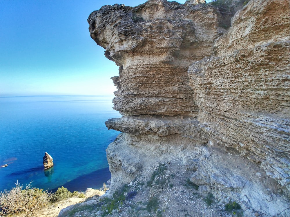 person in yellow shirt sitting on rock formation during daytime