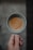 A cozy kitchen scene with a hand holding a beautifully designed ceramic cup filled with coffee.