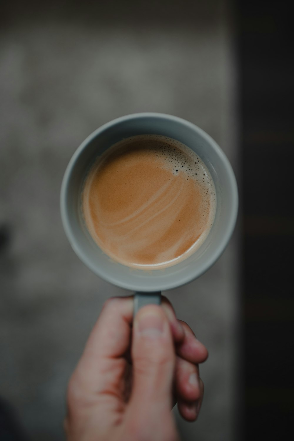 person holding white ceramic mug with brown liquid