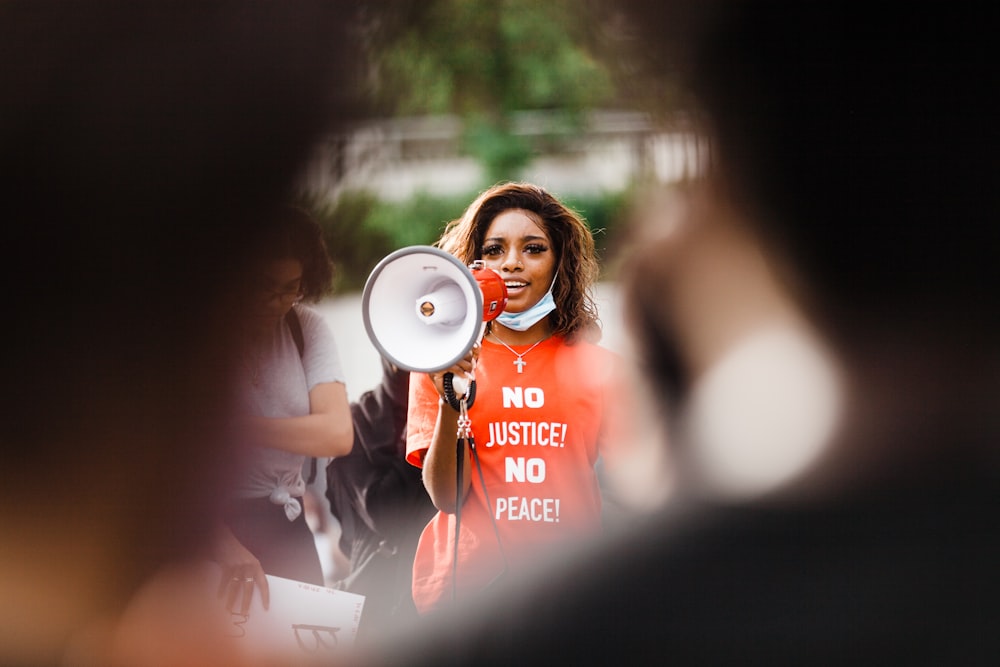 woman in red crew neck t-shirt holding white and blue headphones