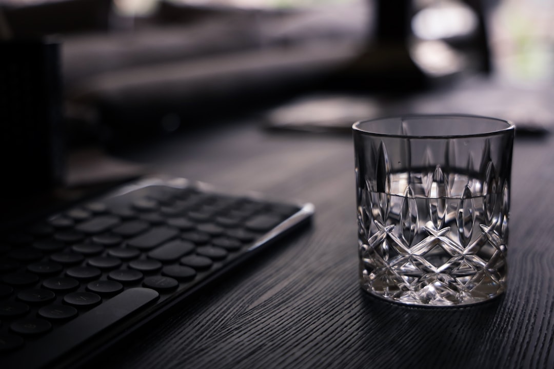 clear drinking glass beside black computer keyboard