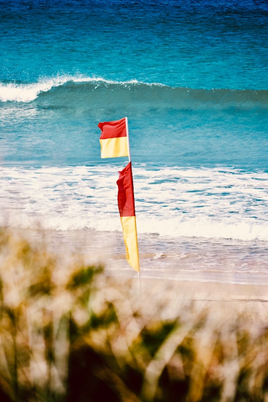 red and white flag on green grass field near body of water during daytime in Gold Coast Australia