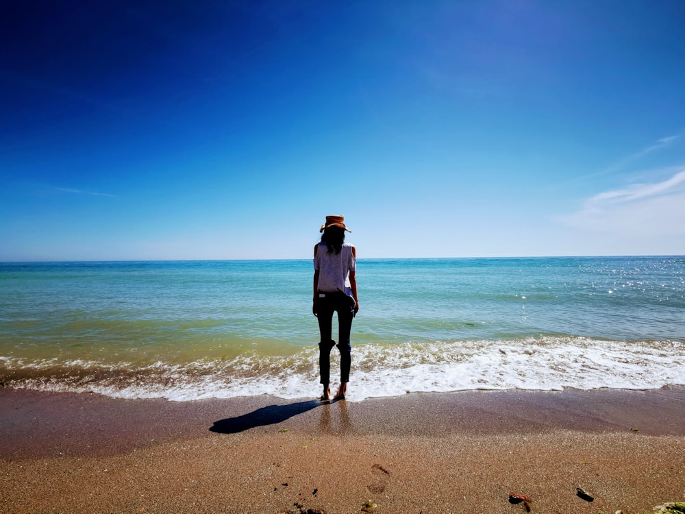 femme en veste noire debout sur la plage pendant la journée