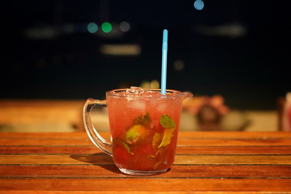 clear glass mug with orange liquid and white straw