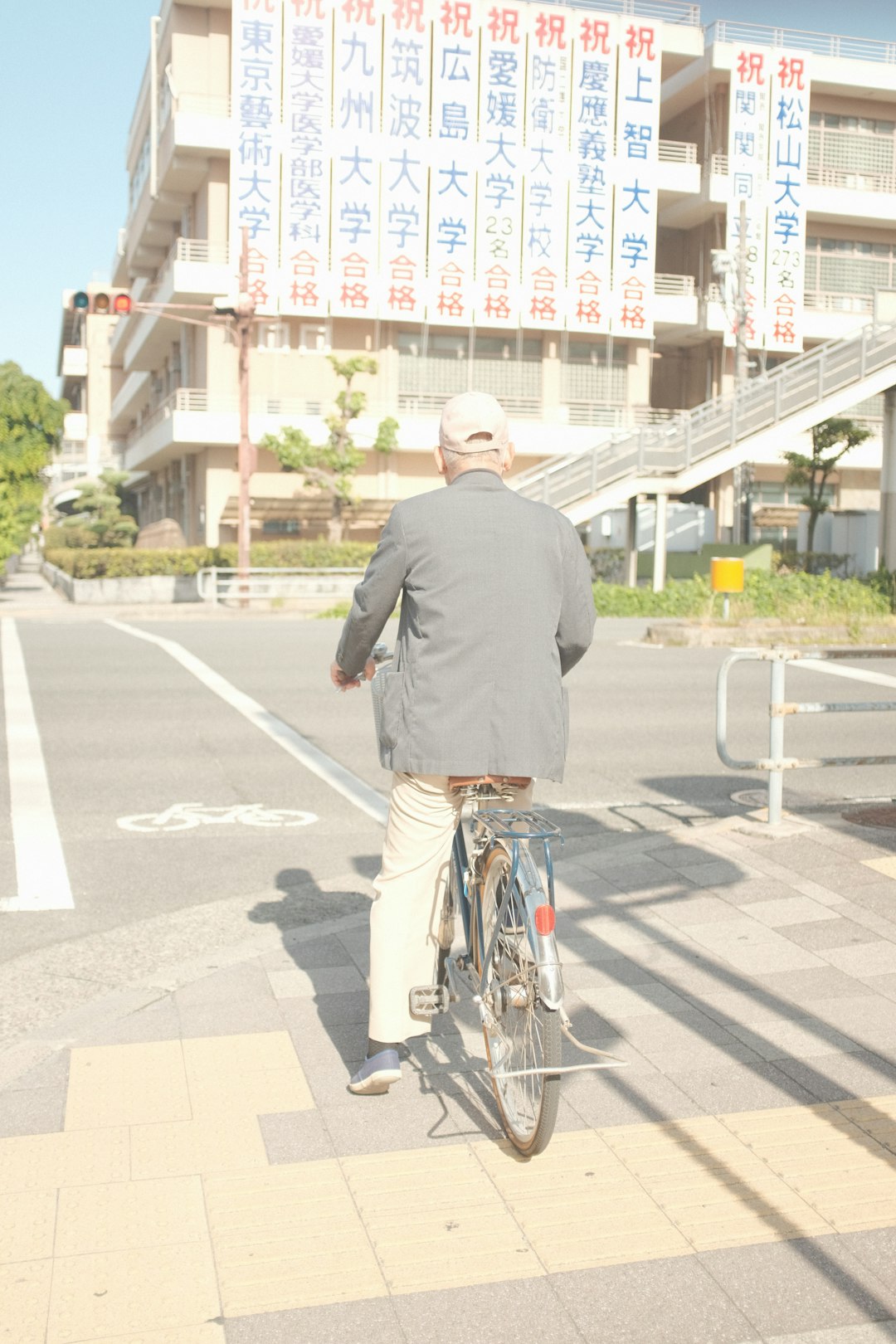 man in gray sweater and blue denim jeans riding bicycle on road during daytime