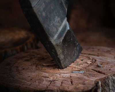 An old, weathered axe embedded in a chopping block surrounded by wood chips.