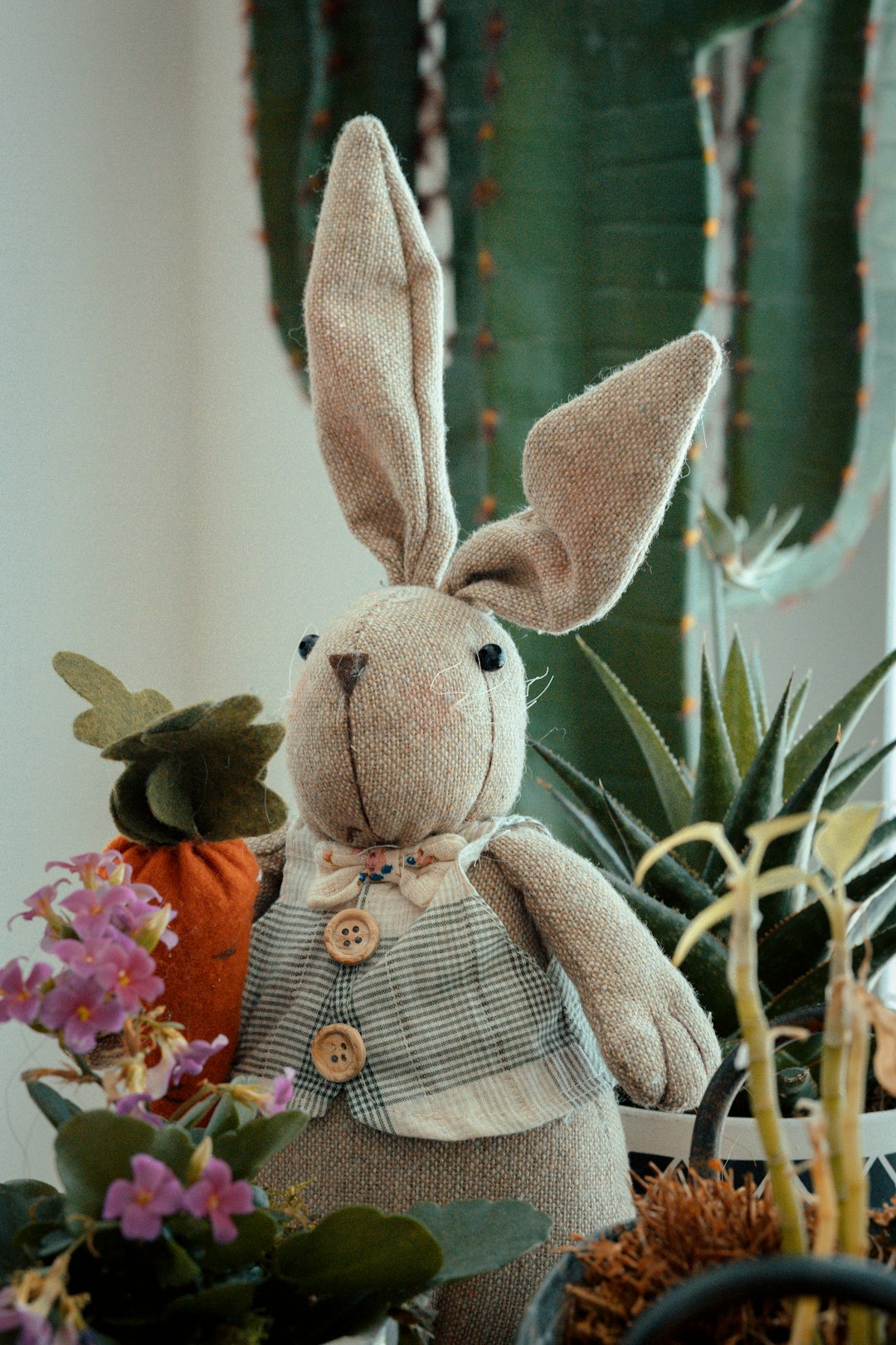gray rabbit plush toy on red and green floral textile