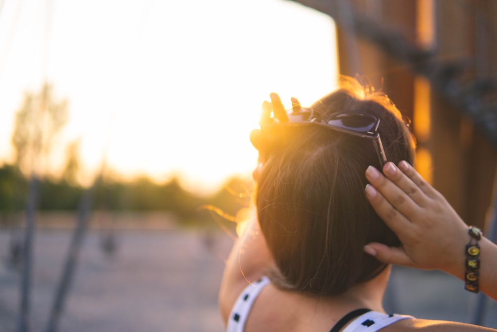 woman in white tank top covering her face with her hands