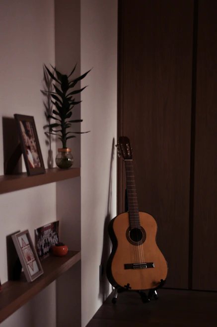 A cozy corner with a guitar resting against a wooden chair beside a small lamp