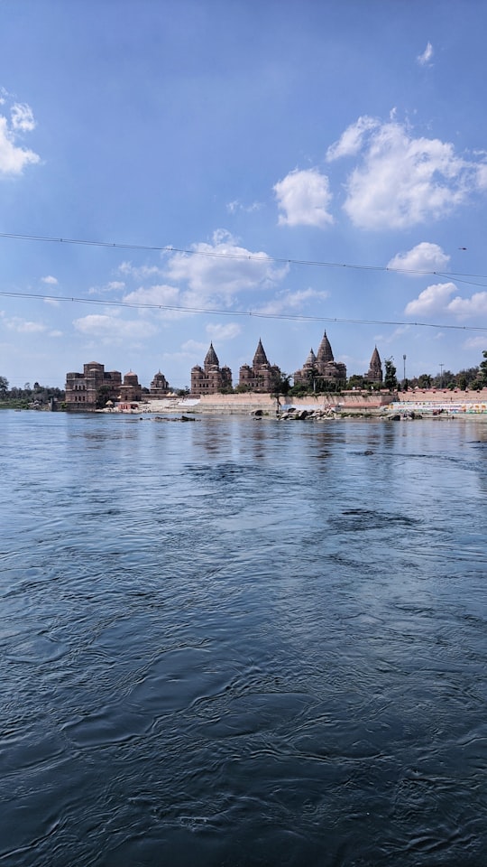 brown concrete building near body of water under blue sky during daytime in Orchha India