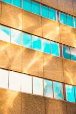 Close-up of a steel and glass facade with navy and gold accents reflecting the city skyline.