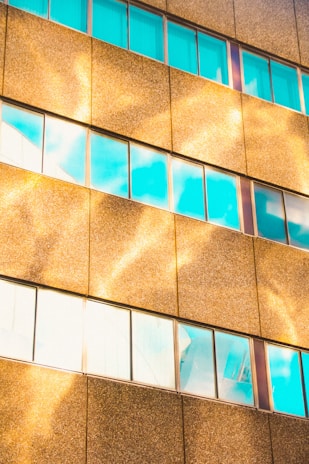 Close-up of a luxury mixed-use building facade featuring gold accents and large glass windows reflecting the cityscape.