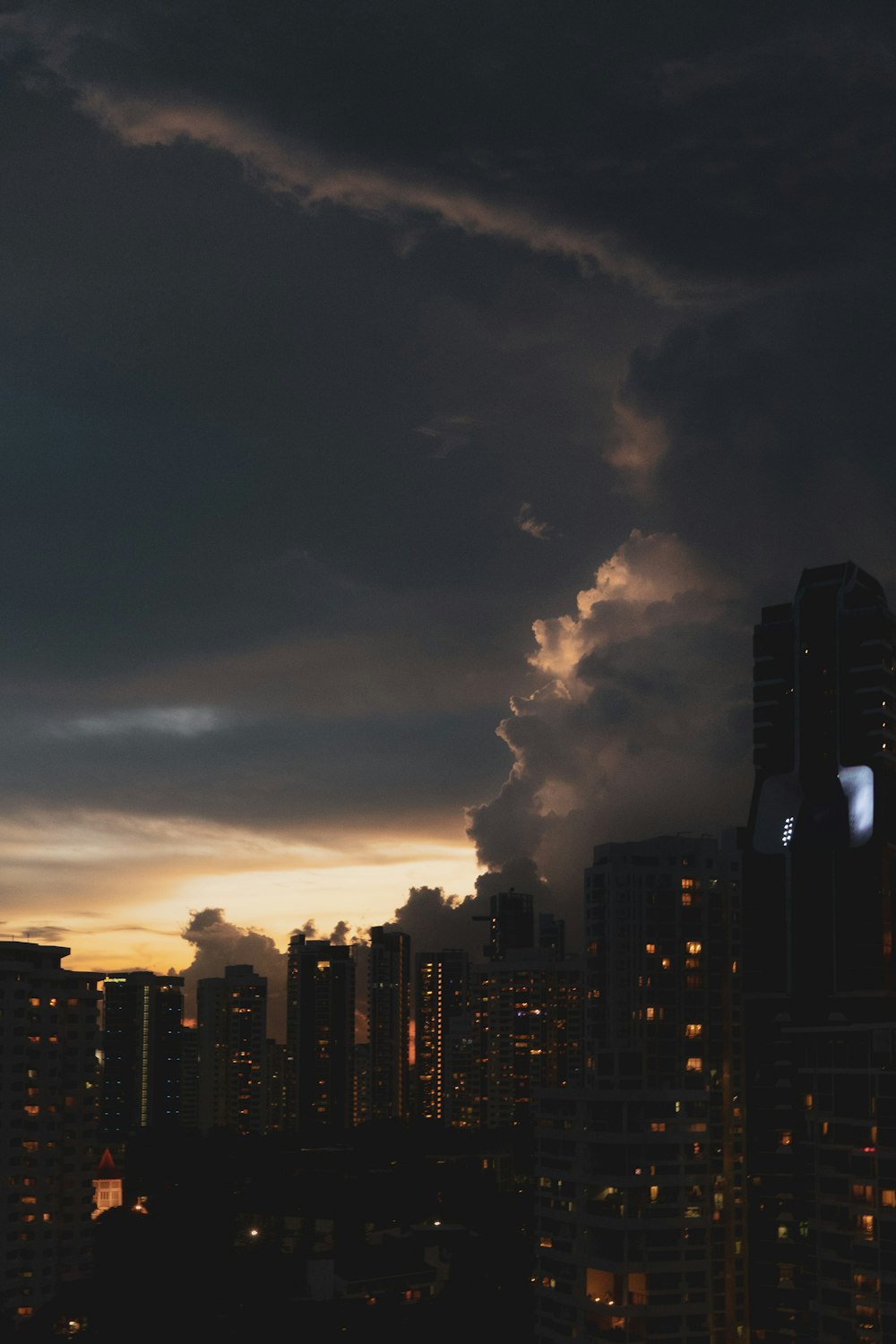 city skyline under cloudy sky during night time