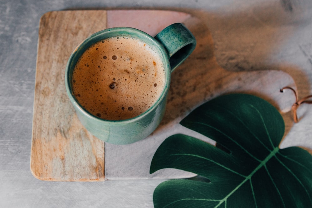 green ceramic mug with brown liquid inside