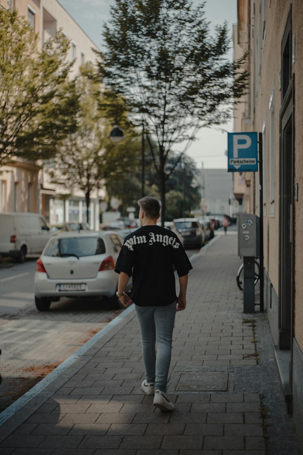 man in black crew neck t-shirt and gray pants walking on sidewalk during daytime