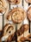 Freshly baked pastries are arranged on a wooden tray, featuring swirls with chocolate and icing drizzles on top. The pastries are golden brown with a flaky texture, and some are twisted in shape, looking crisp and inviting.