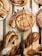 Freshly baked pastries are arranged on a wooden tray, featuring swirls with chocolate and icing drizzles on top. The pastries are golden brown with a flaky texture, and some are twisted in shape, looking crisp and inviting.