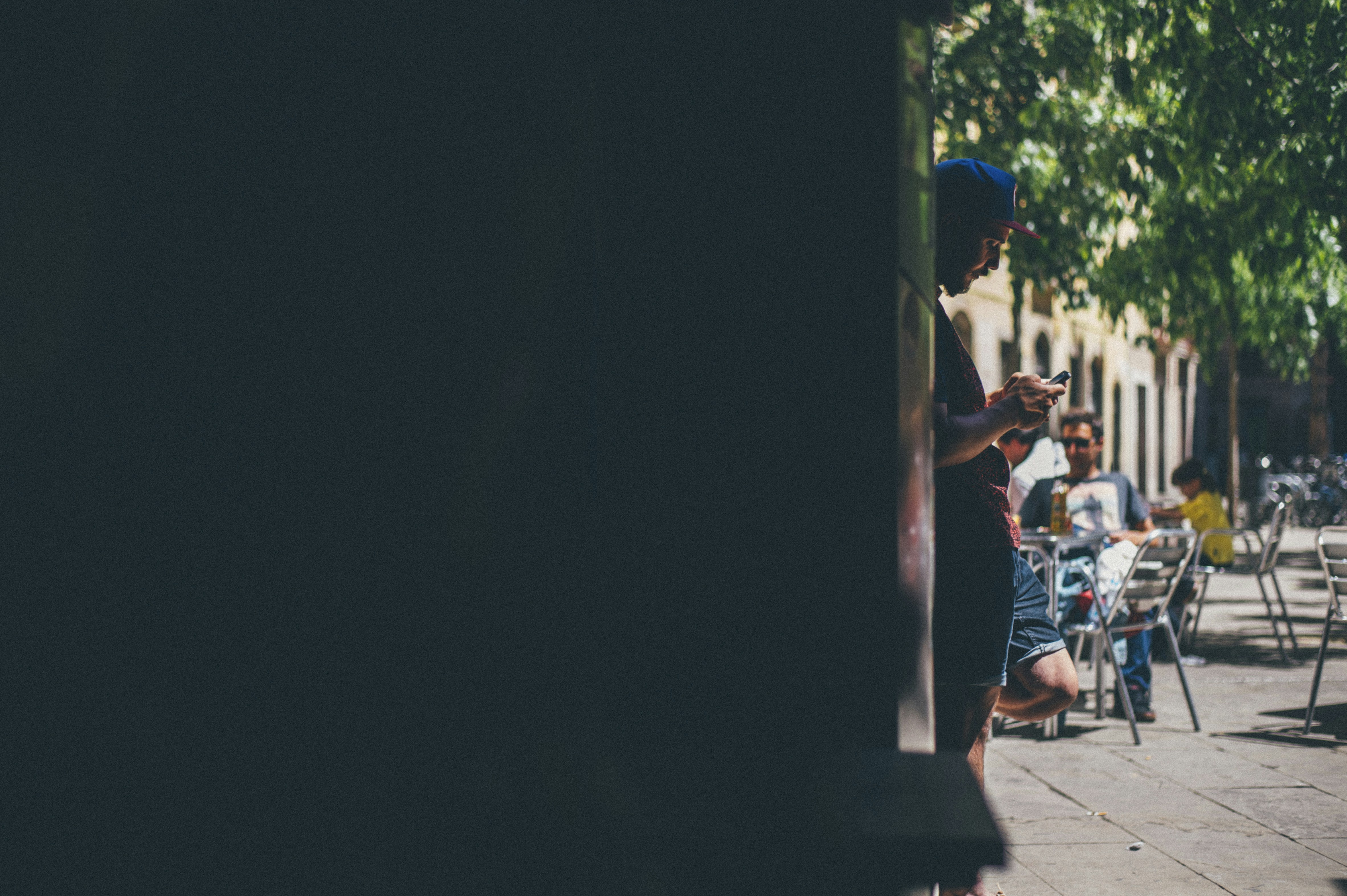 A young man with a mobile phone stands at the entrance to a cafe.