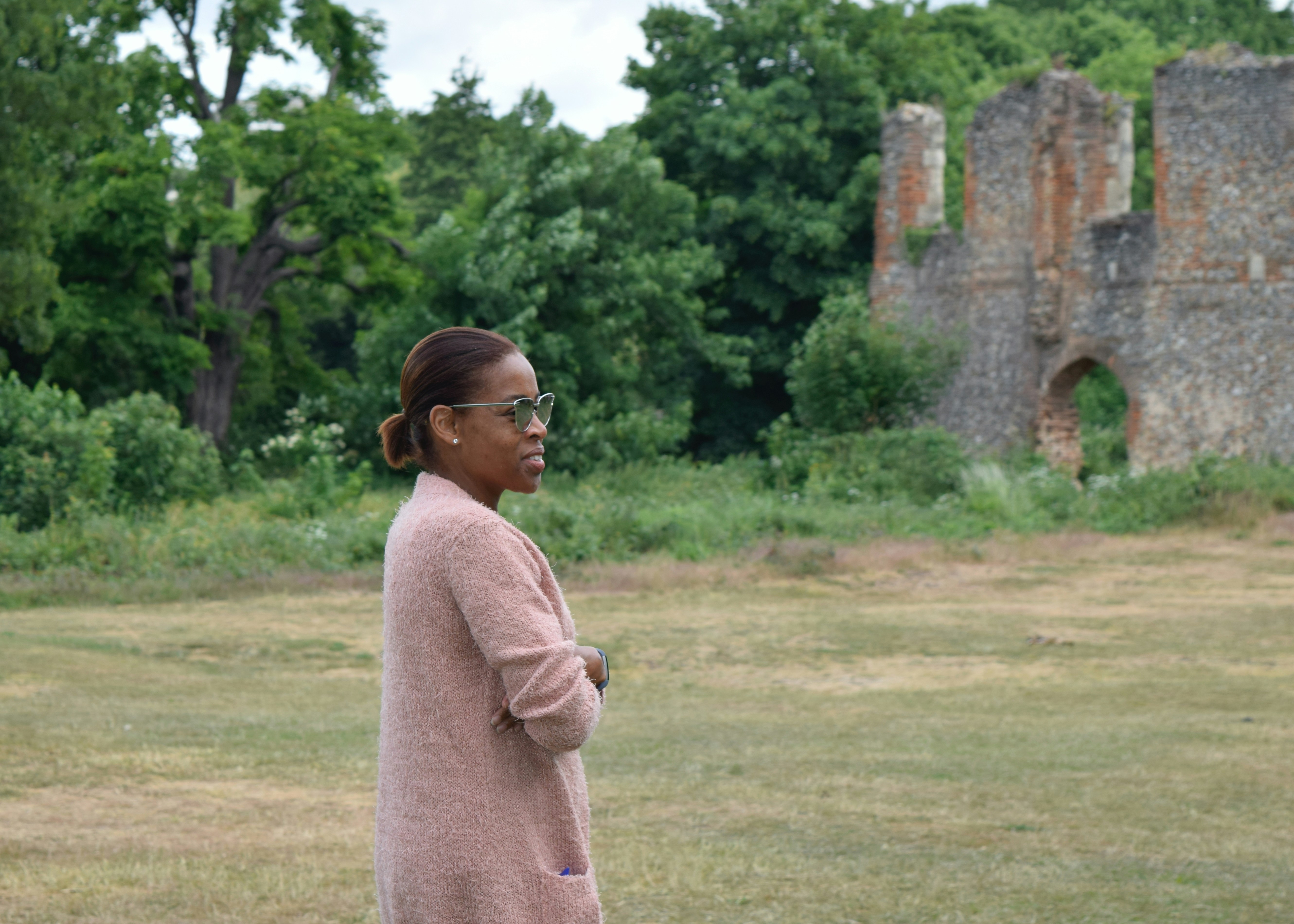 Mujer en camisa rosa de manga larga de pie en el campo de hierba verde durante el día