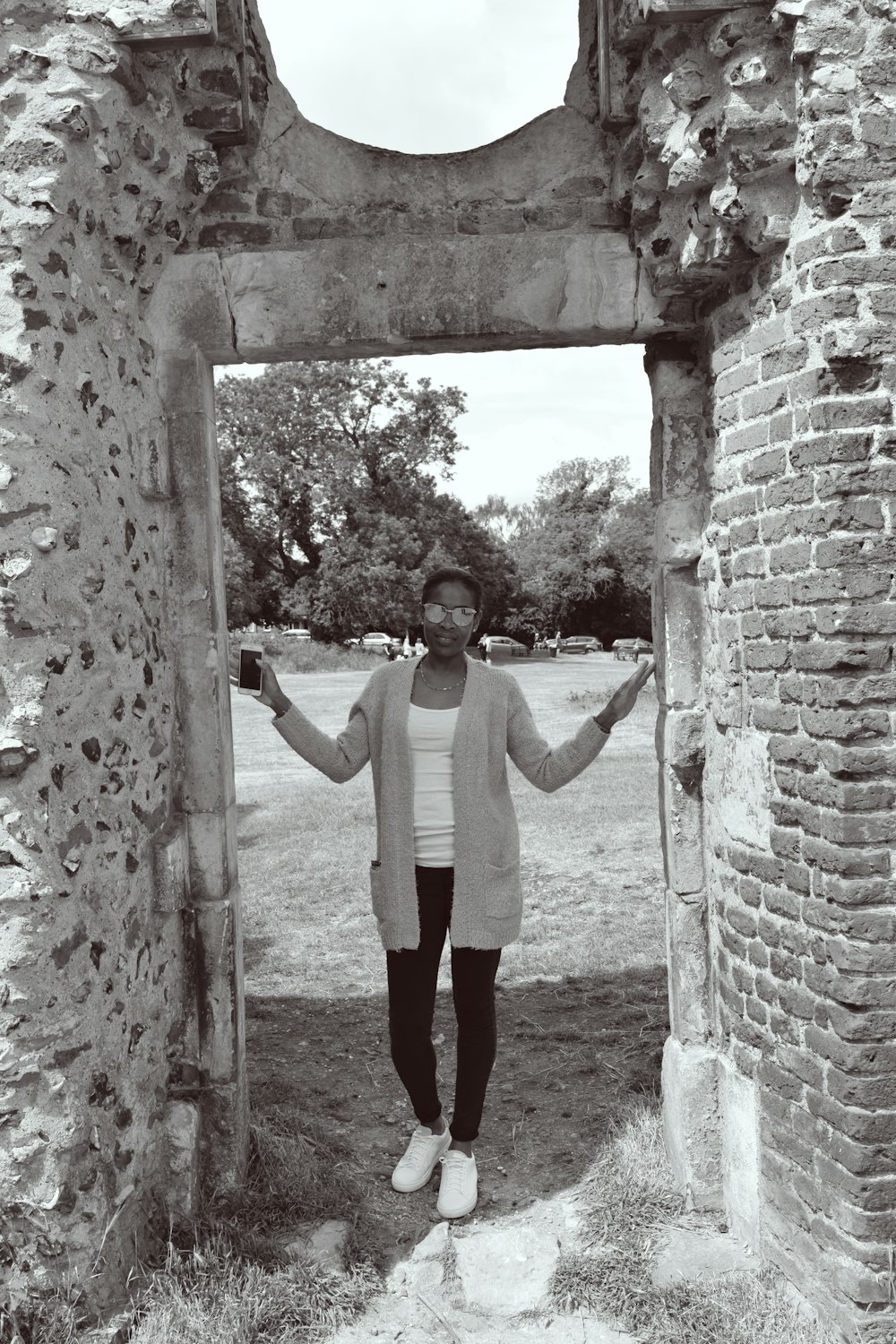 woman in white long sleeve shirt and black pants standing on brown concrete arch during daytime