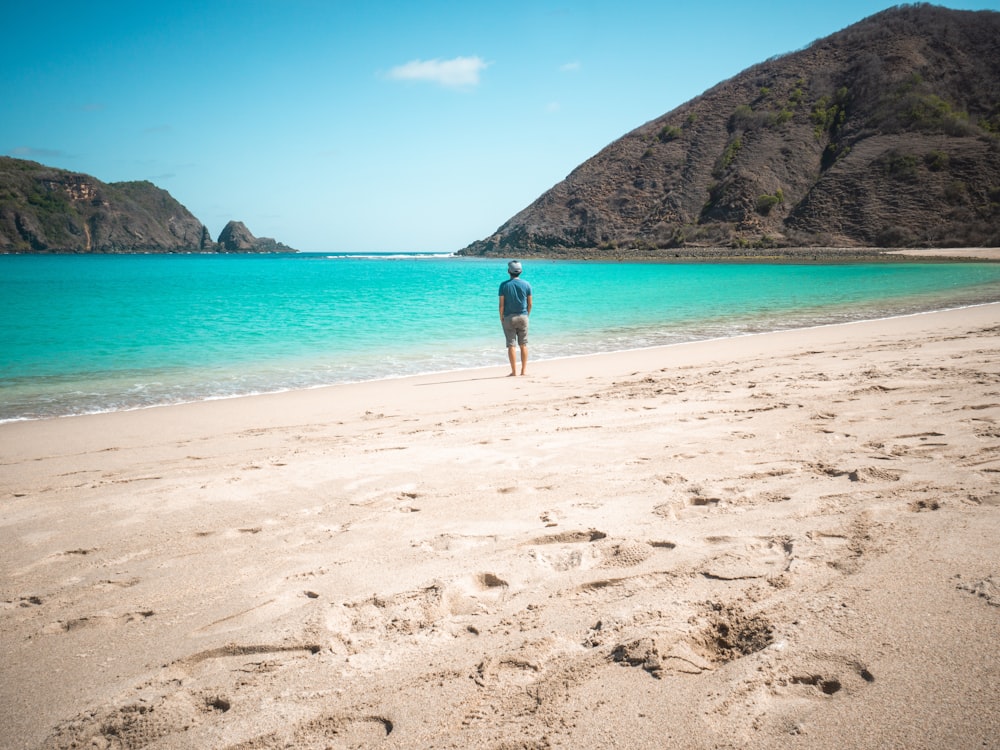 man in blue shorts walking on beach during daytime