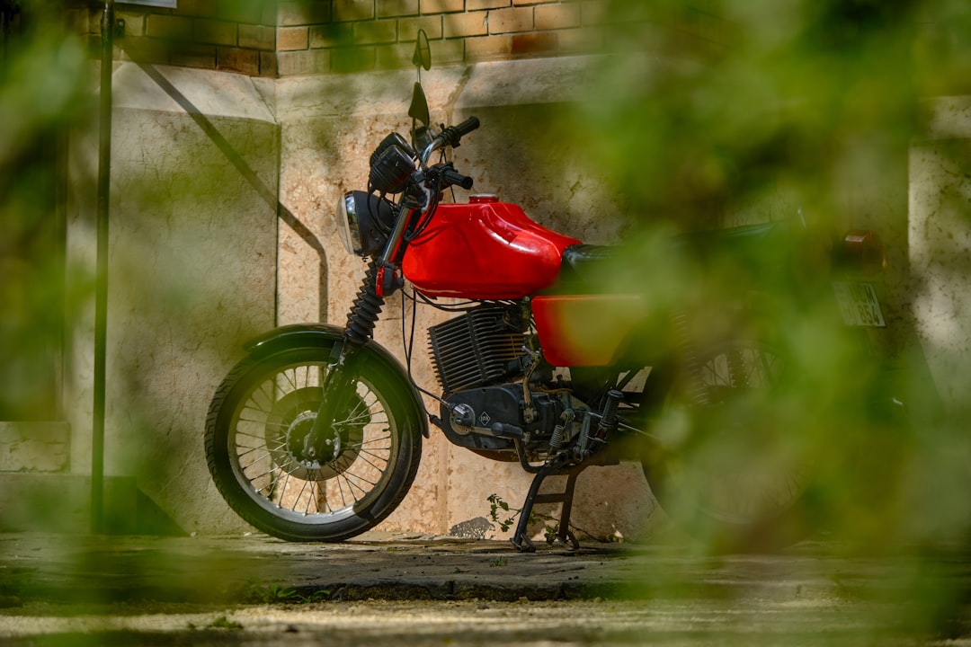 red and black motorcycle parked beside green wall