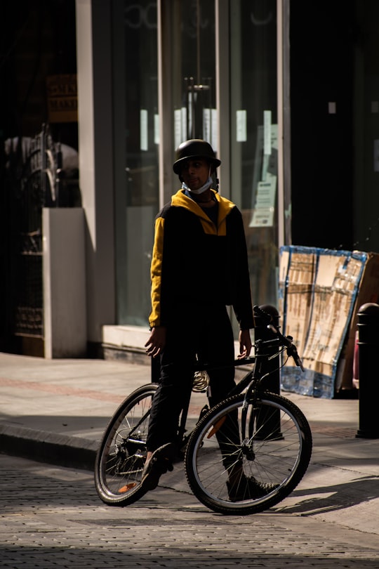 man in black suit jacket and black pants riding on bicycle in Bangalore India