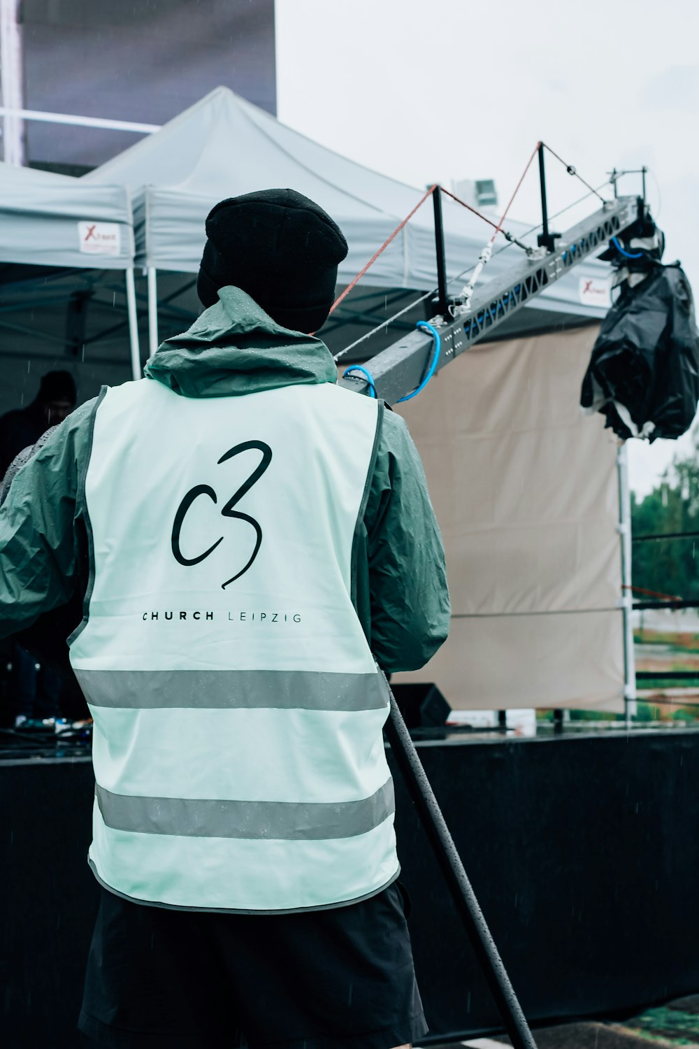 man in white and green hoodie standing near white canopy tent during daytime