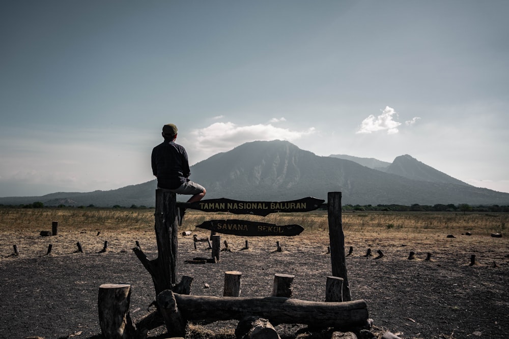 man in black jacket sitting on brown wooden bench during daytime