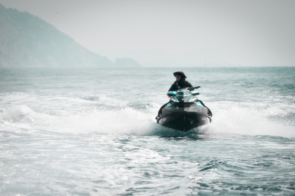 man riding on blue and white personal watercraft on sea during daytime