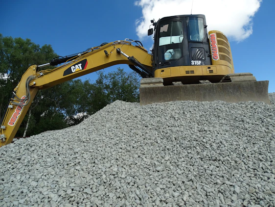 A modern excavator working on a construction site under a clear blue sky in Port Moresby.